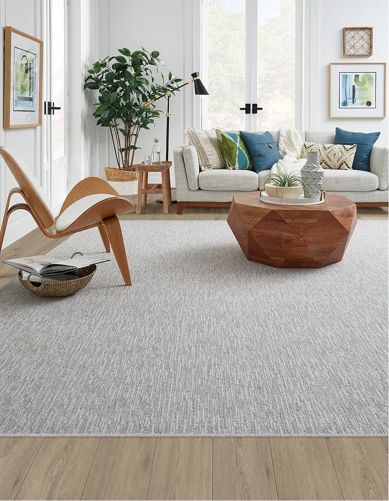 Sunlit living room with a cream loop-pile area rug and sectional sofa.